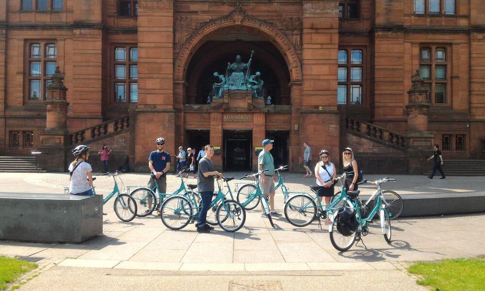 cyclists posing in front of Kelvingrove art gallery Glasgow on a bike tour