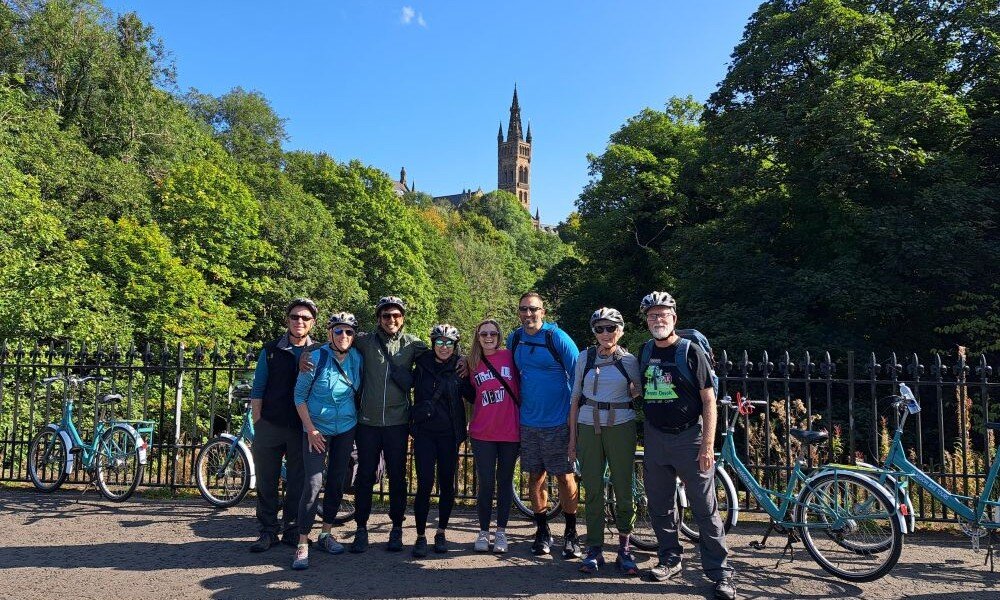 People on bikes n bridge over river Kelvin with Glasgow University behind